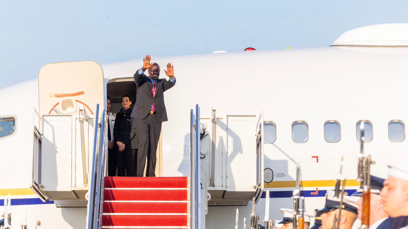 a man waving from the stairs of a plane